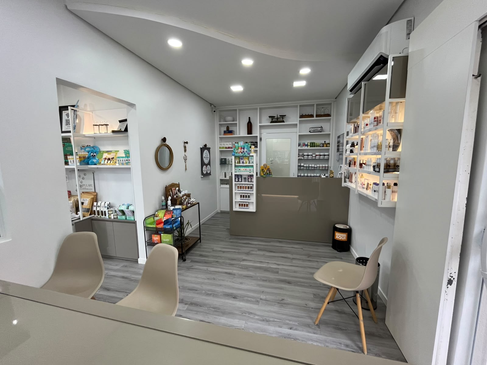 Interior da farmácia Manipulare — recepção com cadeiras, balcão e produtos